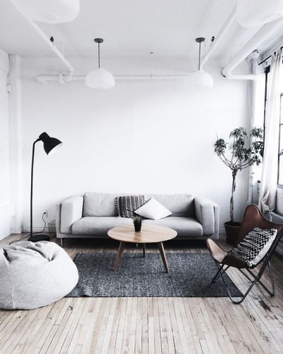 sala grande com sofá cinza, pufe, cadeira e planta