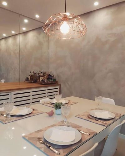 Sala de jantar com textura de cimento queimado e luminária rose gold