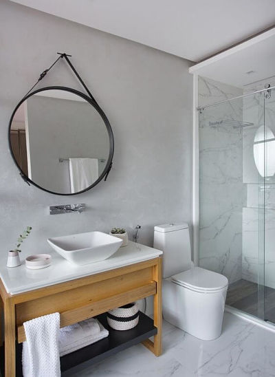 Espelho redondo estilo adnet em banheiro simples.