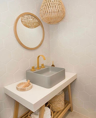 Espelho redondo com moldura de madeira em parede de banheiro com revestimento hexagonal.