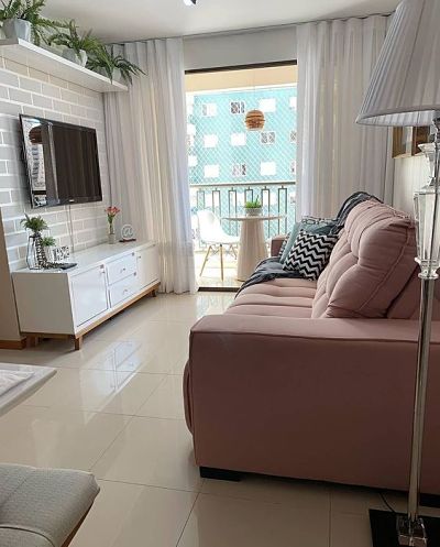 Sala pequena de apartamento com sofá rosa claro
