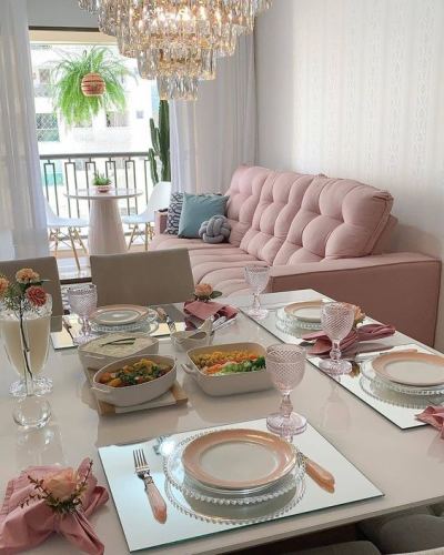 Sofa retrátil rosa em sala pequena com mesa de jantar