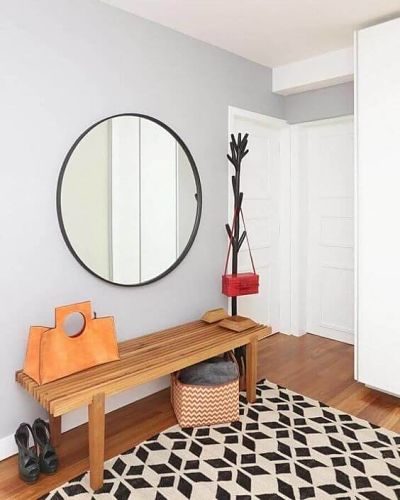Espelho redondo na entrada de casa com banco e tapete