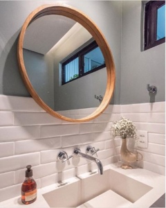 Espelho redondo com moldura de madeira no banheiro com revestimento metro white