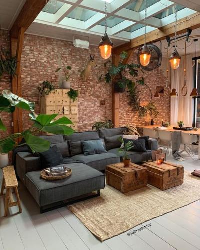 Decoração rústica e moderna com sofá preto e parede de tijolinho e objetos rústicos