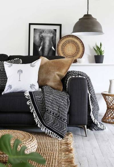 Sofá preto com almofadas e manta 