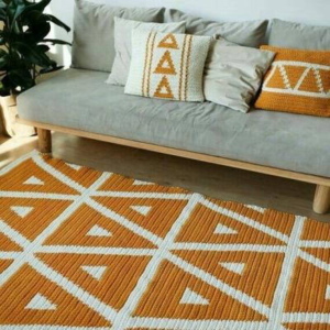 Tapete colorido geométrico e almofadas no sofá cinza