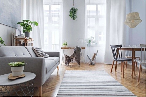 Sala pequena estilo escandinavo minimalista com sofá cinza e tapete