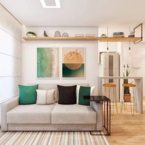 Decoração de sala pequena com sofá cinza e almofadas, quadros e mesa lateral