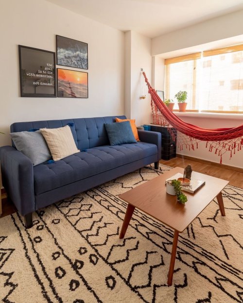 Sala pequena com sofá azul e rede de descanso