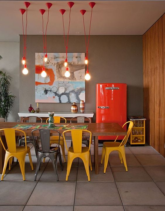 sala de jantar decorada com cadeiras amarelas e luminária vermelha