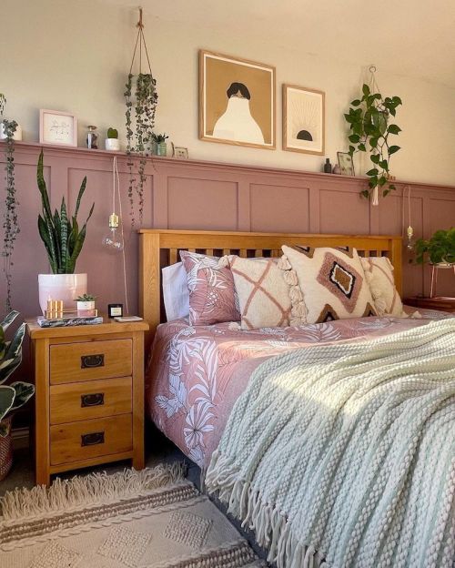 Quarto com pintura de meia parede rosa, cama com almofadas e mesa lateral