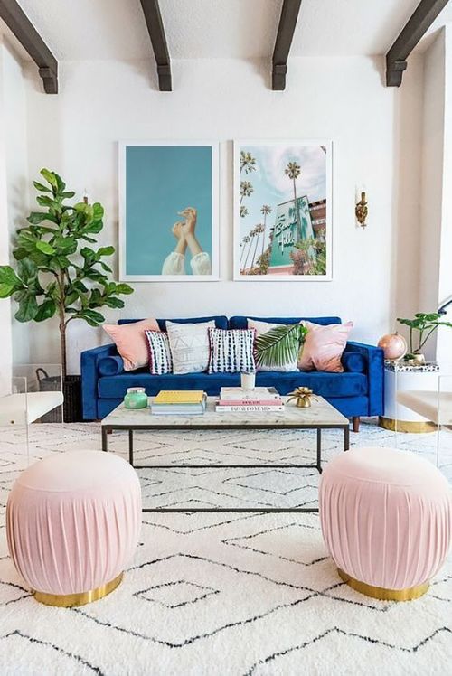 Cores que combinam com rosa: sala com sofá azul, dois quadros na parede, mesa de centro com puffs rosa e tapete grande