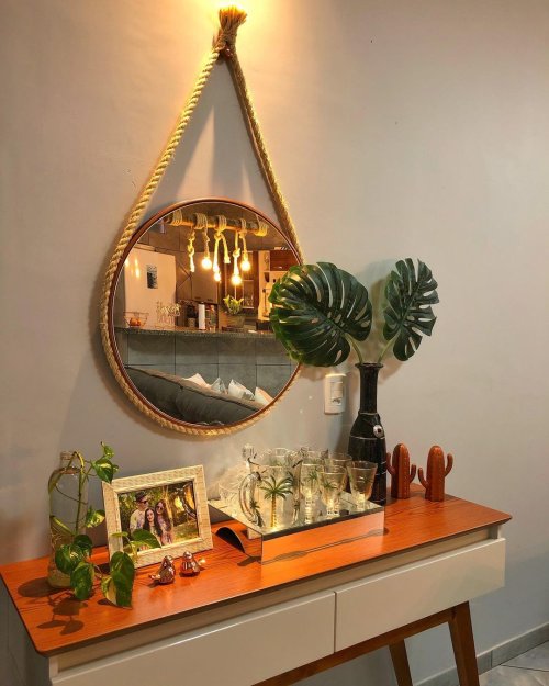 Decoração para aparador de sala de estar com planta e espelho redondo